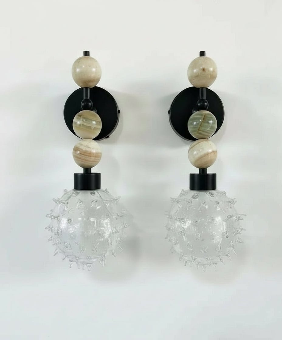 Pair of wall sconces with glass globes and beaded accents on a white background