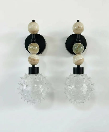 Pair of wall sconces with glass globes and beaded accents on a white background