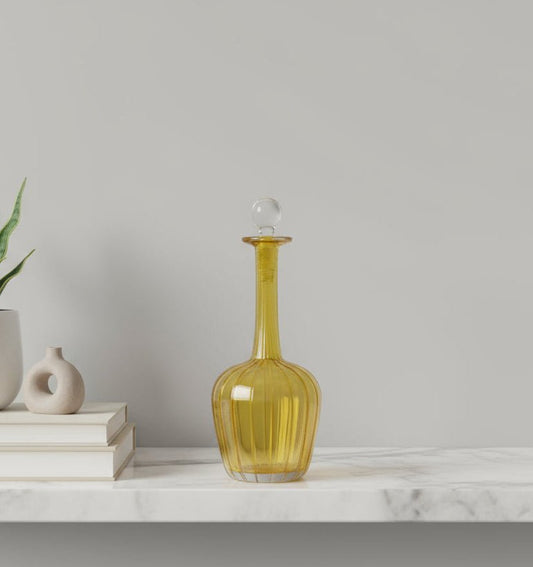 Yellow glass decanter on a marble surface with a neutral background