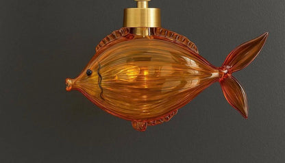 Fish-shaped amber glass light fixture on a dark background