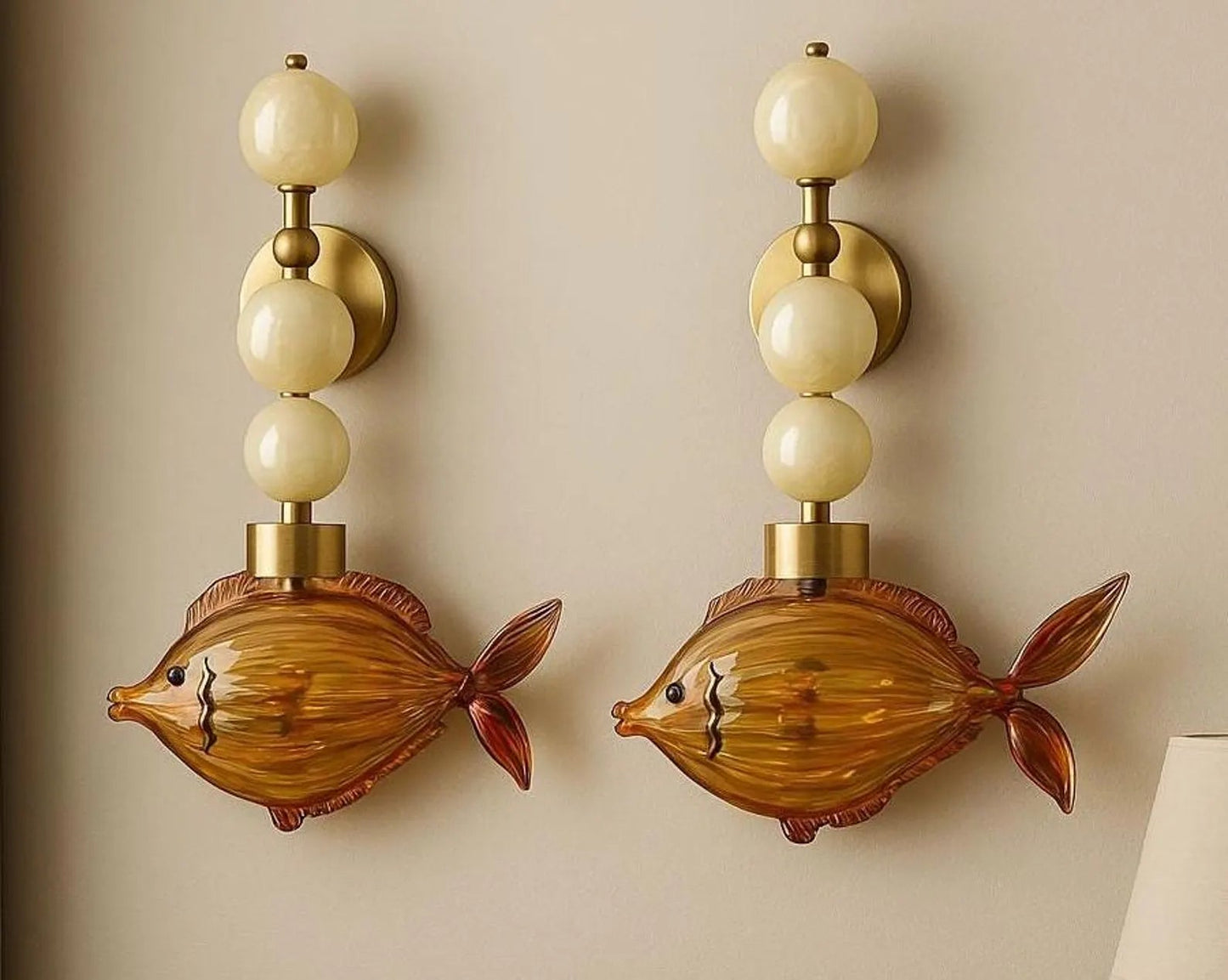 Two fish-shaped wall sconces with beige lampshades on a beige wall.