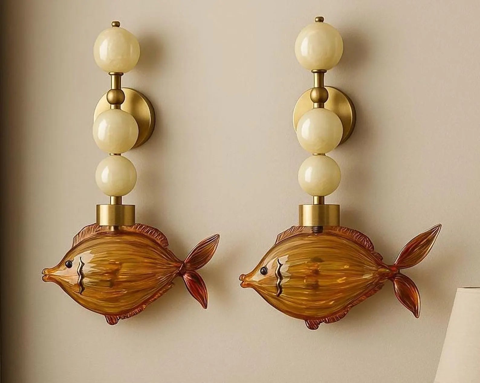 Two fish-shaped wall sconces with beige lampshades on a beige wall.