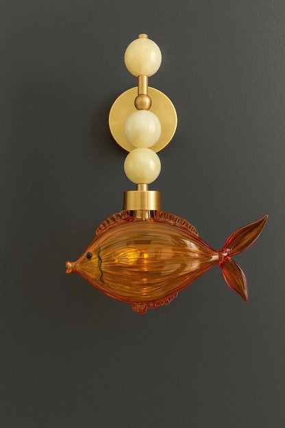 Decorative wall sconce with fish design on a dark background