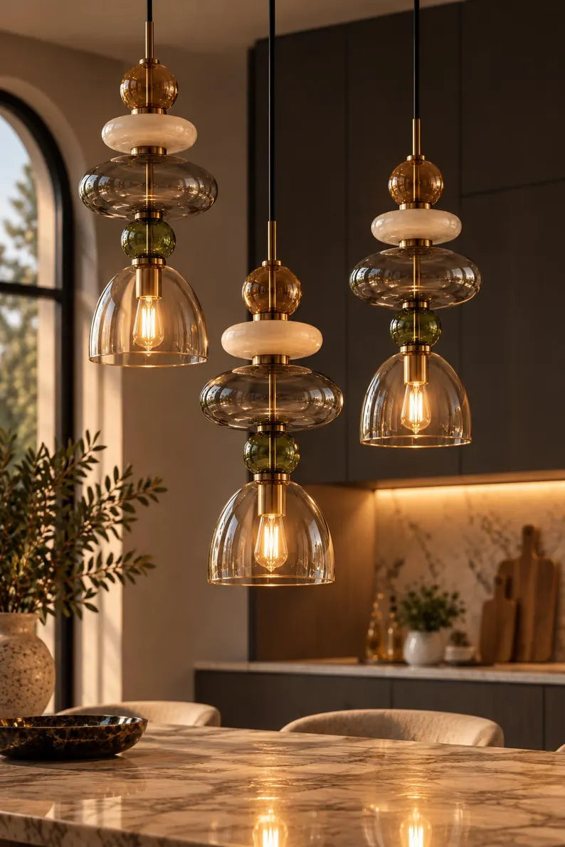 Handmade glass pendant light featuring amber, milky white, smoky grey and olive green glass elements, with brass accents and a clear champagne glass shade | Les Trois Pyramides