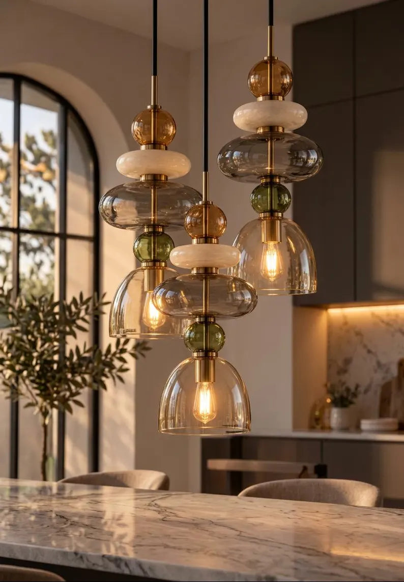 Handmade glass pendant light featuring amber, milky white, smoky grey and olive green glass elements, with brass accents and a clear champagne glass shade | Les Trois Pyramides