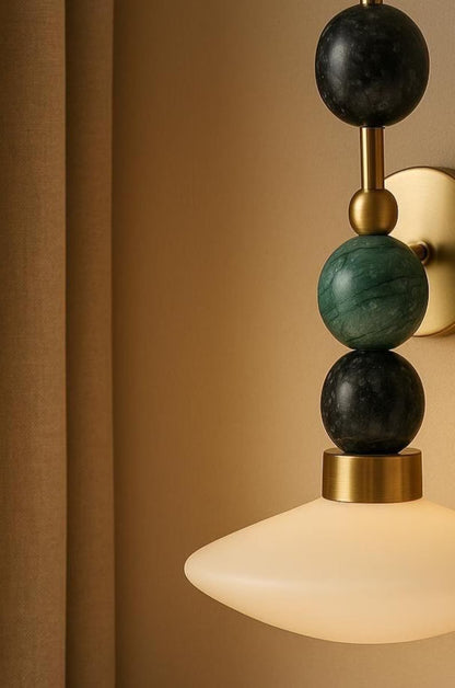 Decorative wall light fixture with spherical design on a beige wall.