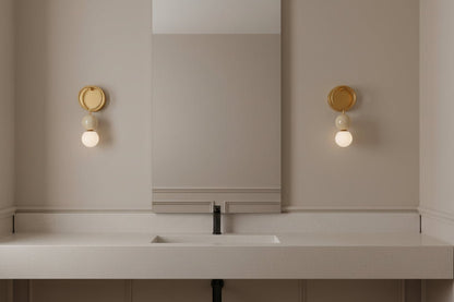 Marble and brass wall sconce with frosted glass installed above bathroom mirror
