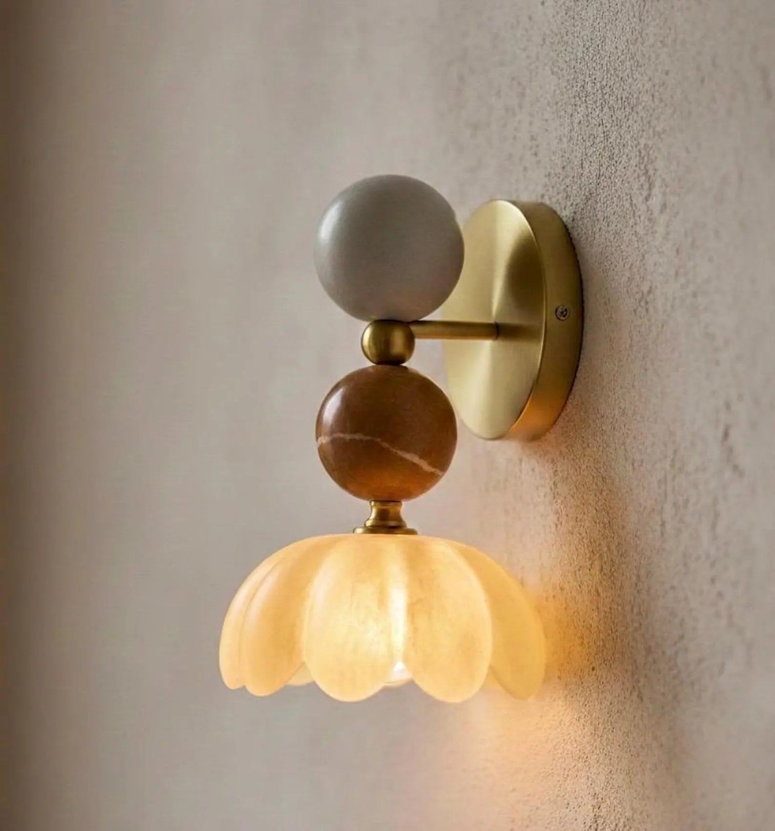 Wall-mounted light fixture with decorative elements on a textured wall
