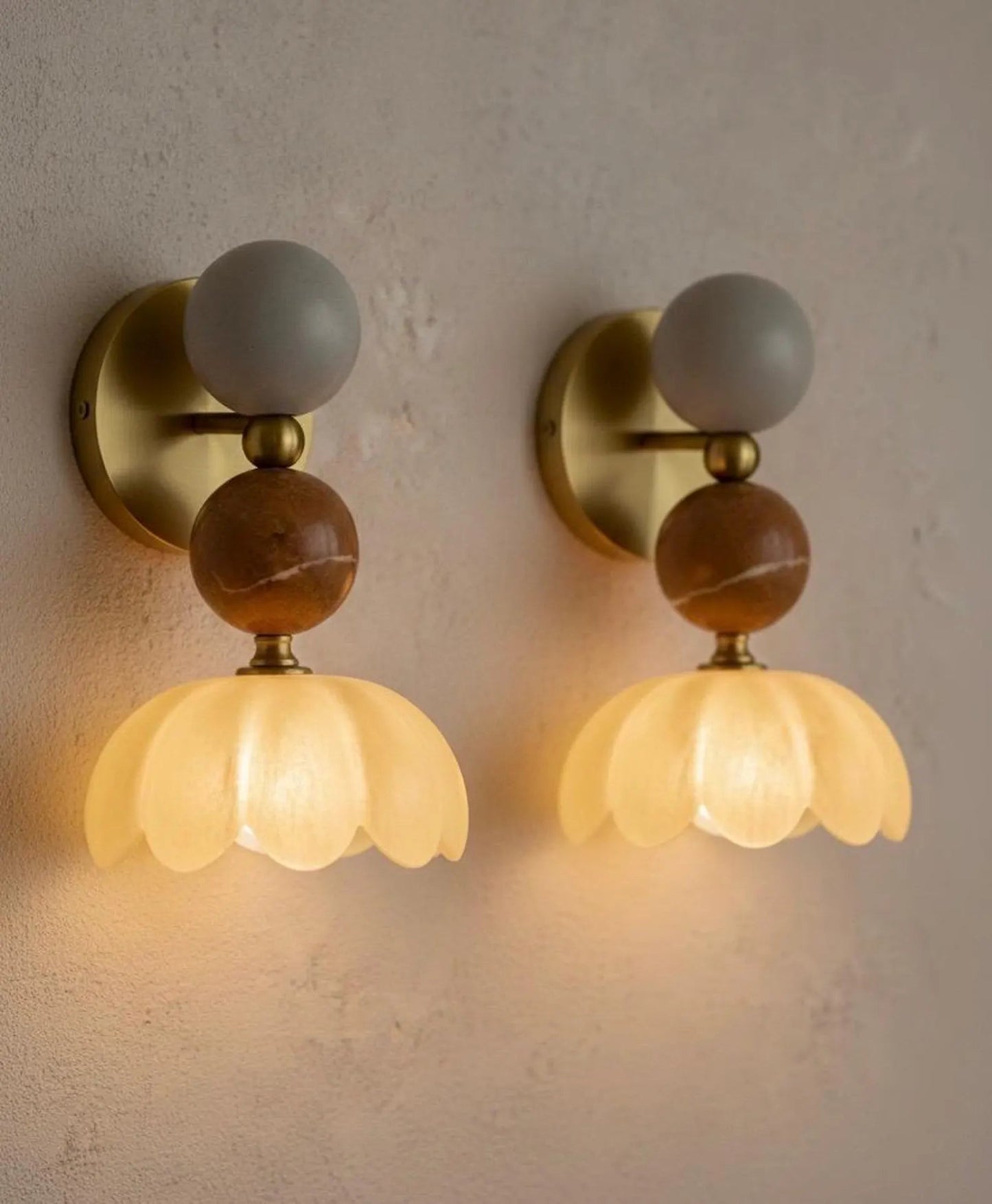 Two wall sconces with decorative glass shades on a neutral wall.