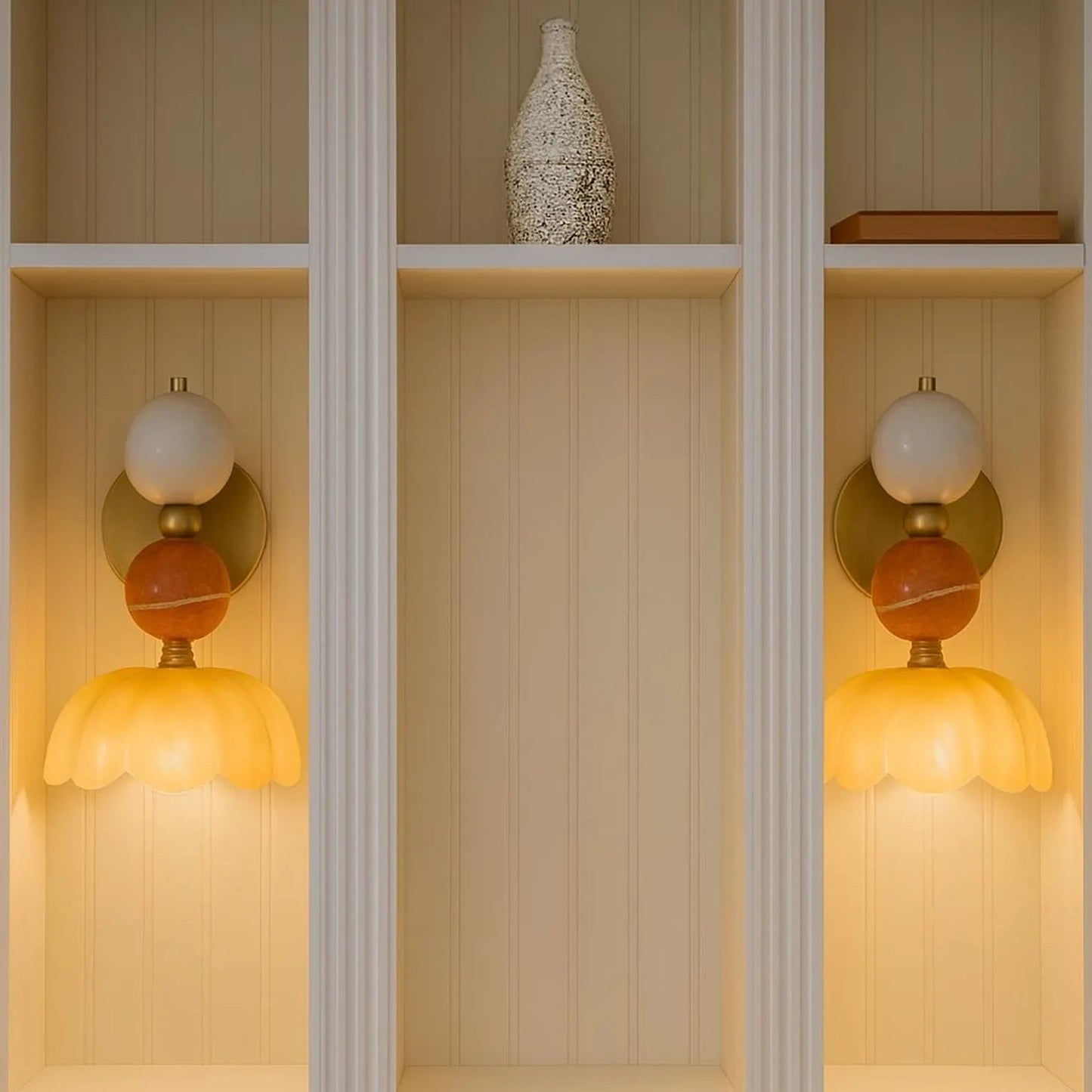 Decorative wall sconces with orange and gold shades on a wooden shelf.
