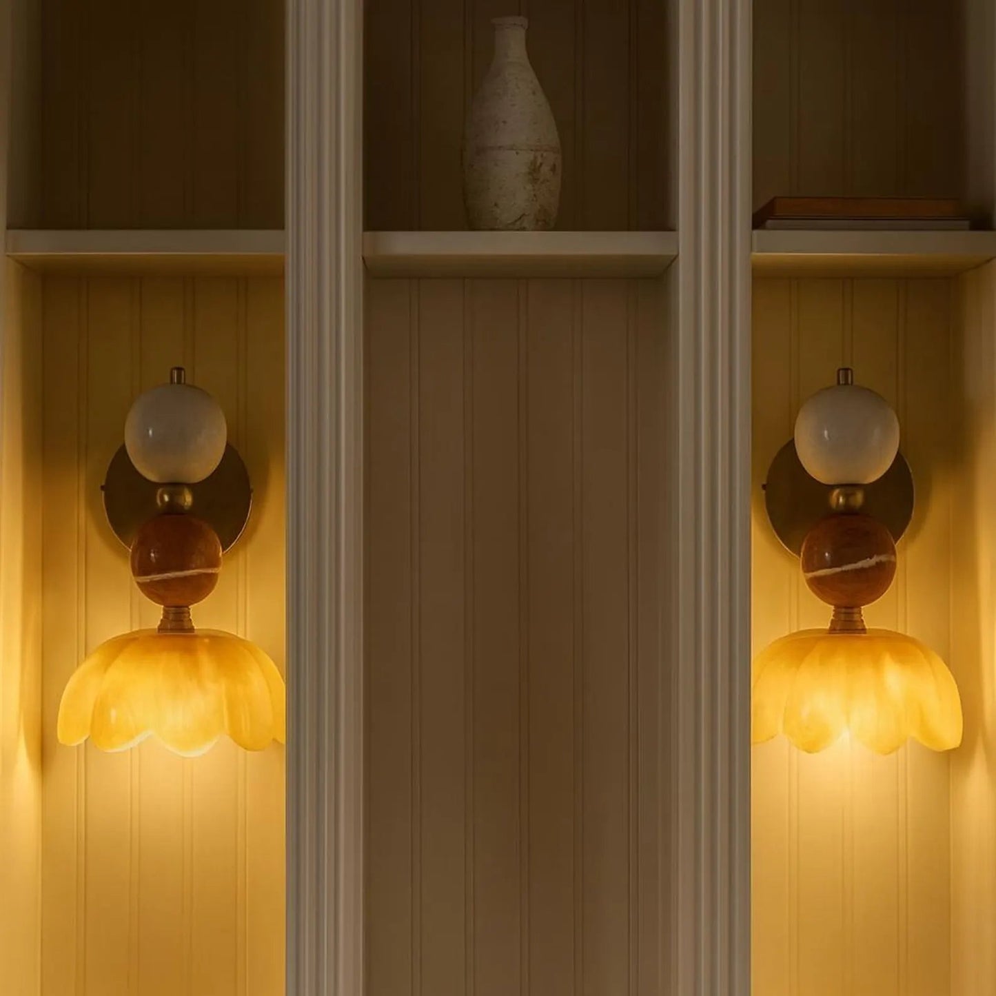 Decorative wall sconces with floral designs on a wooden shelf.