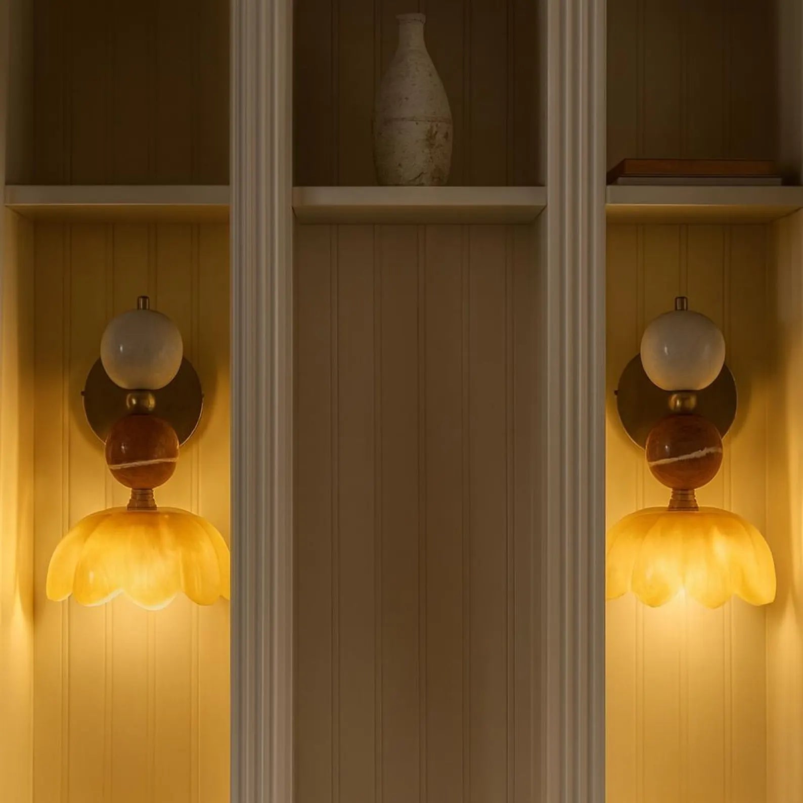Decorative wall sconces with floral designs on a wooden shelf.