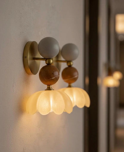 Wall-mounted light fixture with colorful glass shades on a neutral wall.