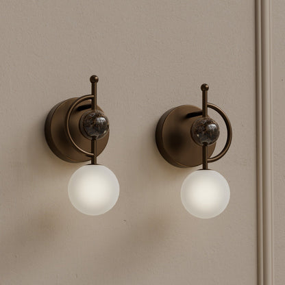 Pair of marble wall sconces with frosted glass globes installed on interior wall
