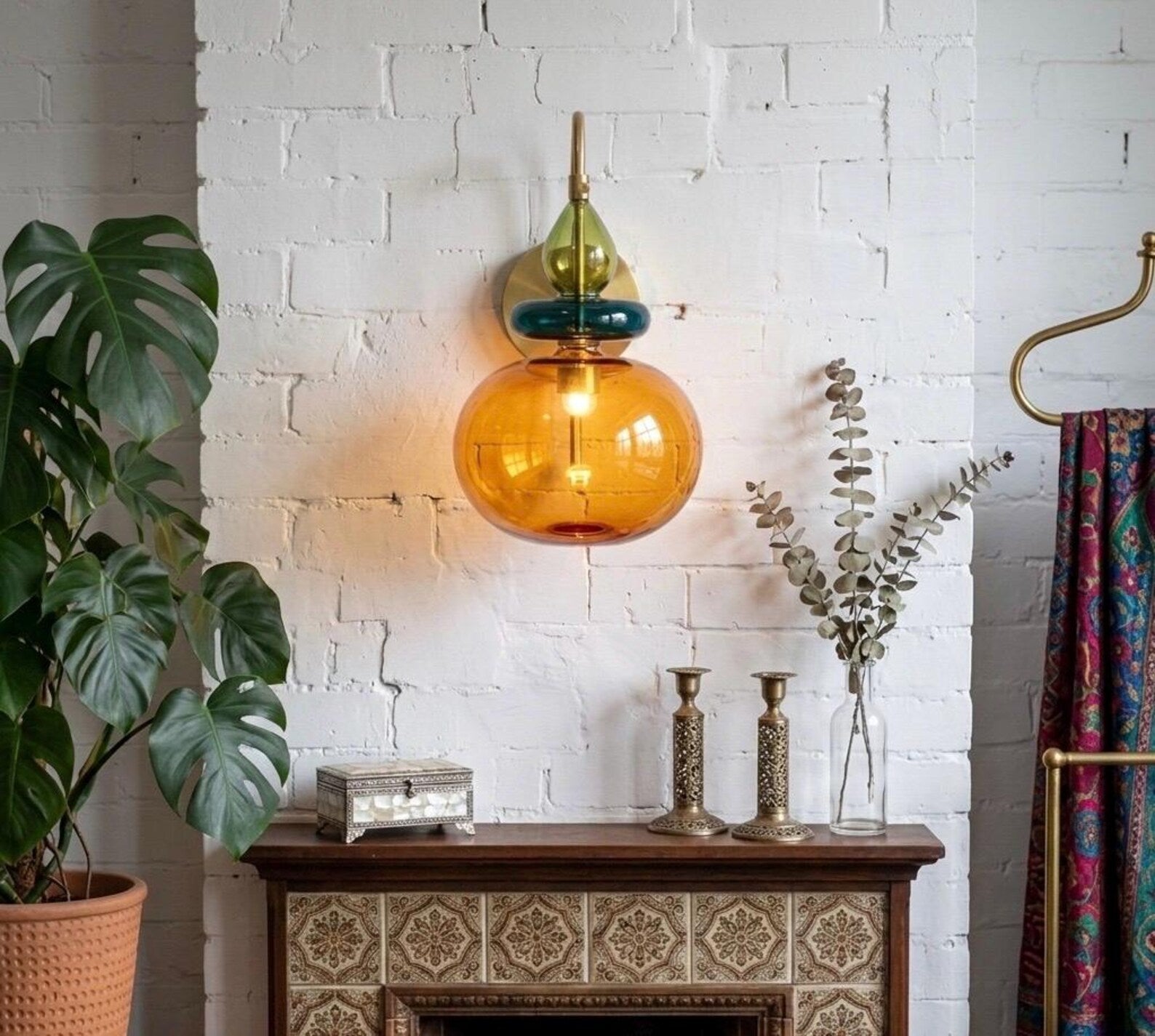 Decorative glass pendant light hanging above a wooden console table with a white brick wall background.