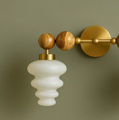 Wall-mounted light fixture with wooden and brass accents on a green background