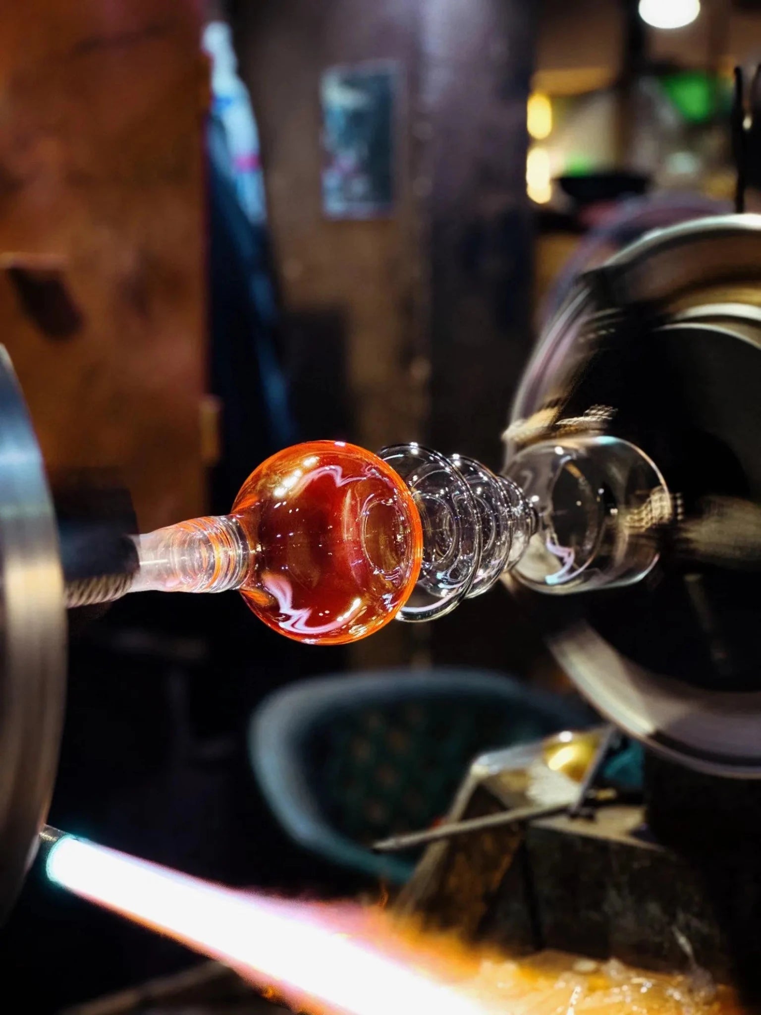 Glassblowing process with molten glass being shaped.