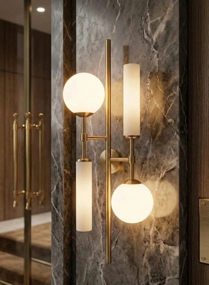 Modern wall sconces with glass shades on a marble wall.