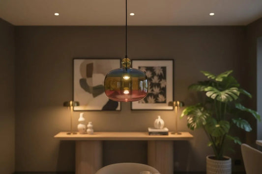 Modern interior with a colorful pendant light, table, and plant.