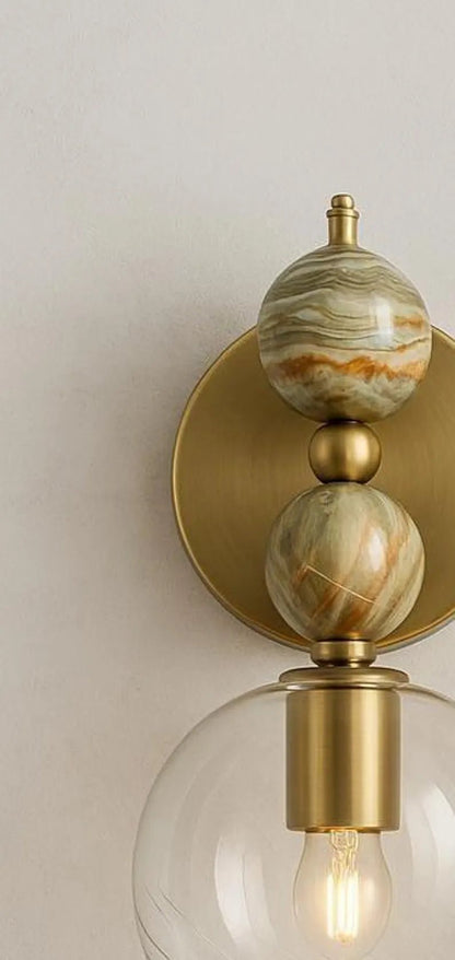 Pair of wall sconces with onyx, gold finish and glass globes on a neutral background | Les Trois Pyramides
