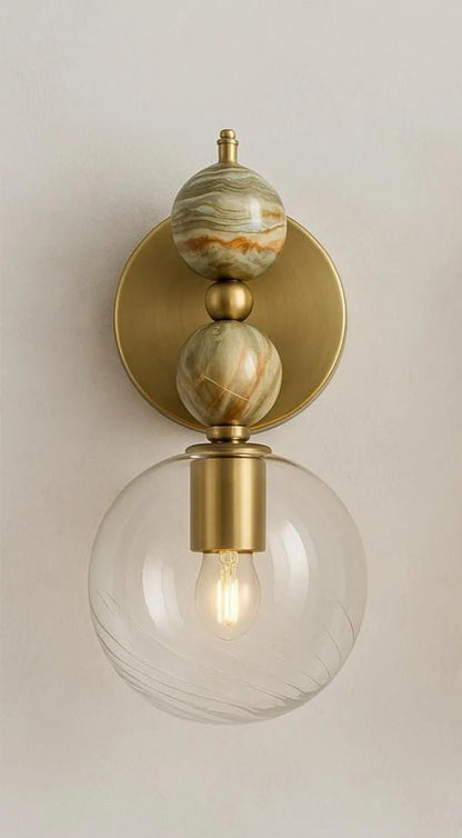 Pair of wall sconces with onyx, gold finish and glass globes on a neutral background | Les Trois Pyramides