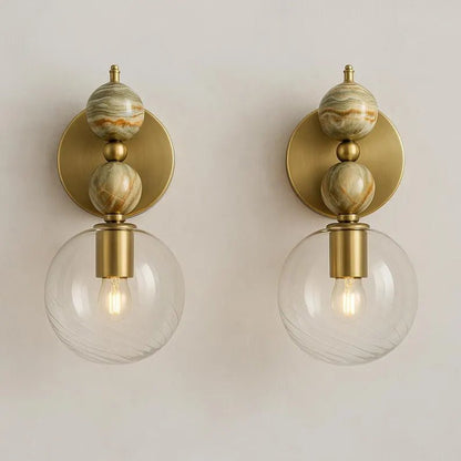 Pair of wall sconces with onyx, gold finish and glass globes on a neutral background | Les Trois Pyramides
