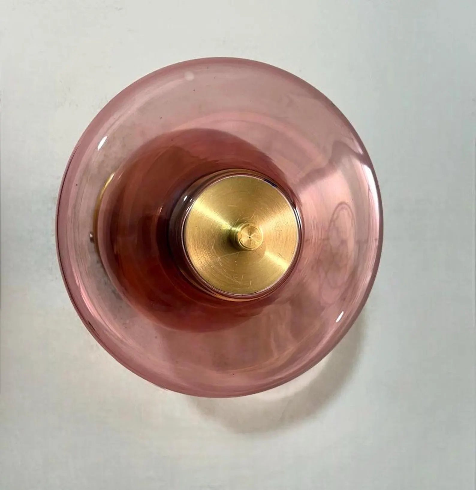 Pink glass object with gold base on a white background