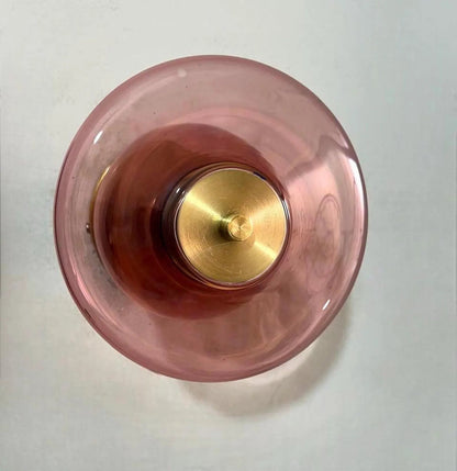Pink glass object with gold base on a white background