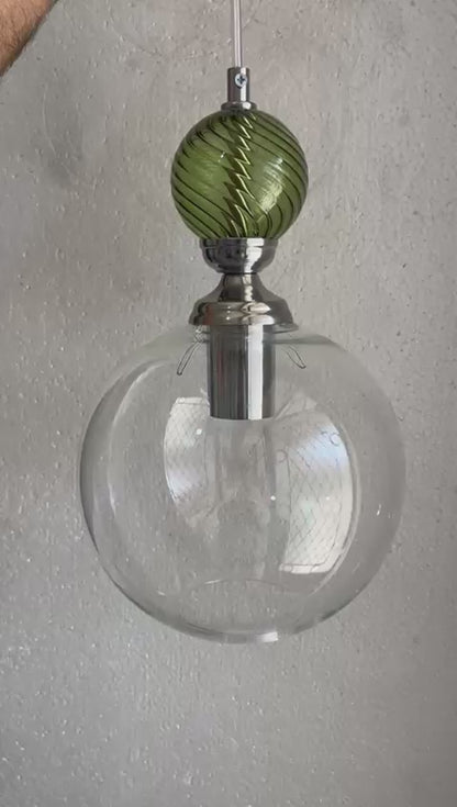 Modern pendant lights with glass shades and green accents hanging - Les Trois Pyramides