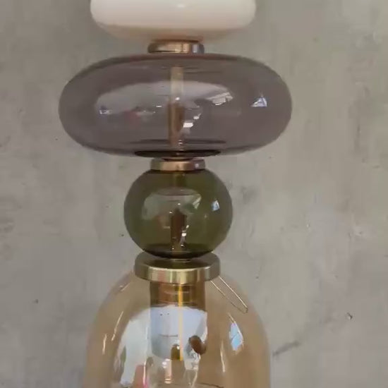 Handmade glass pendant light featuring amber, milky white, smoky grey and olive green glass elements, with brass accents and a clear champagne glass shade | Les Trois Pyramides