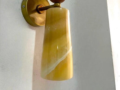 Wall sconce with a yellow glass shade and gold metal fixture.