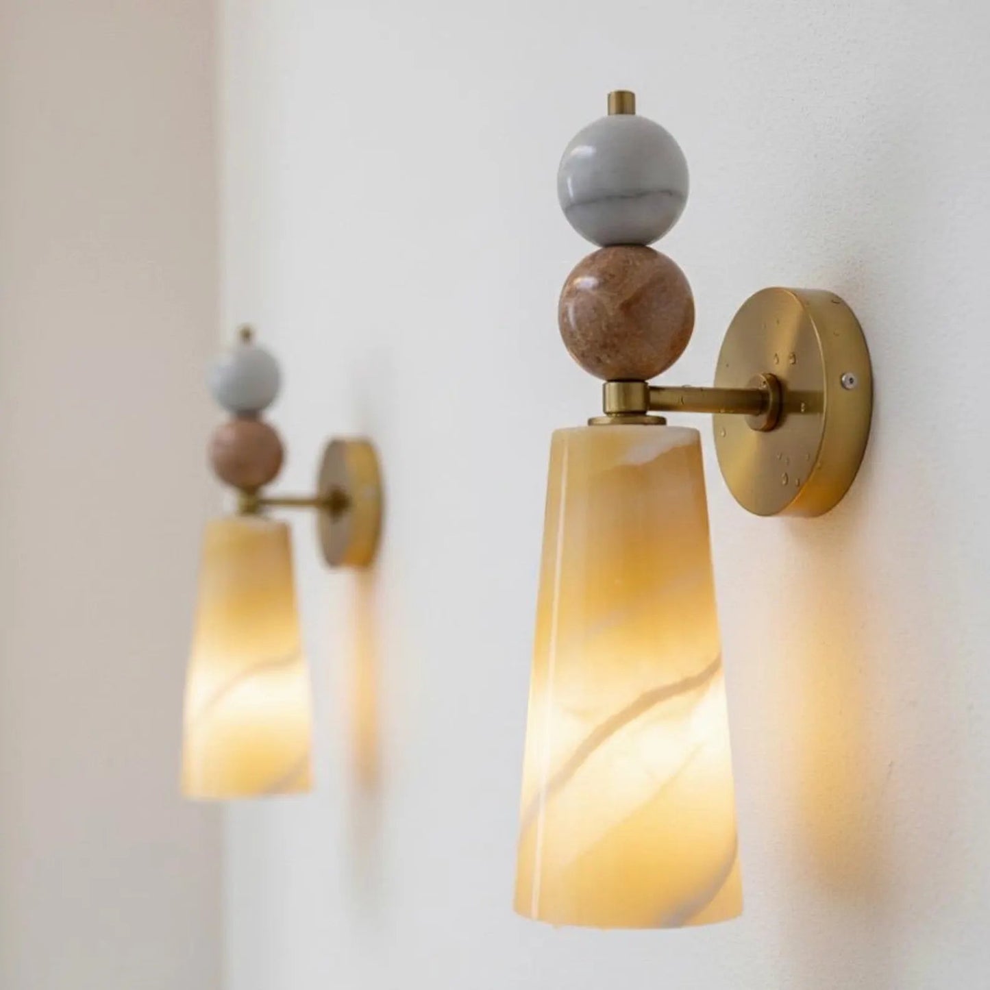 Wall sconces with marble-like shades and gold accents 