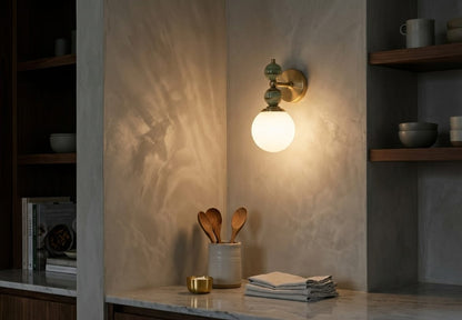 Hand adjusting a wall-mounted light fixture with marble accents on a plain wall.