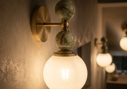 Hand adjusting a wall-mounted light fixture with marble accents on a plain wall.
