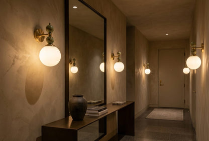 Hand adjusting a wall-mounted light fixture with marble accents on a plain wall.