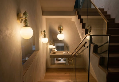 Hand adjusting a wall-mounted light fixture with marble accents on a plain wall.