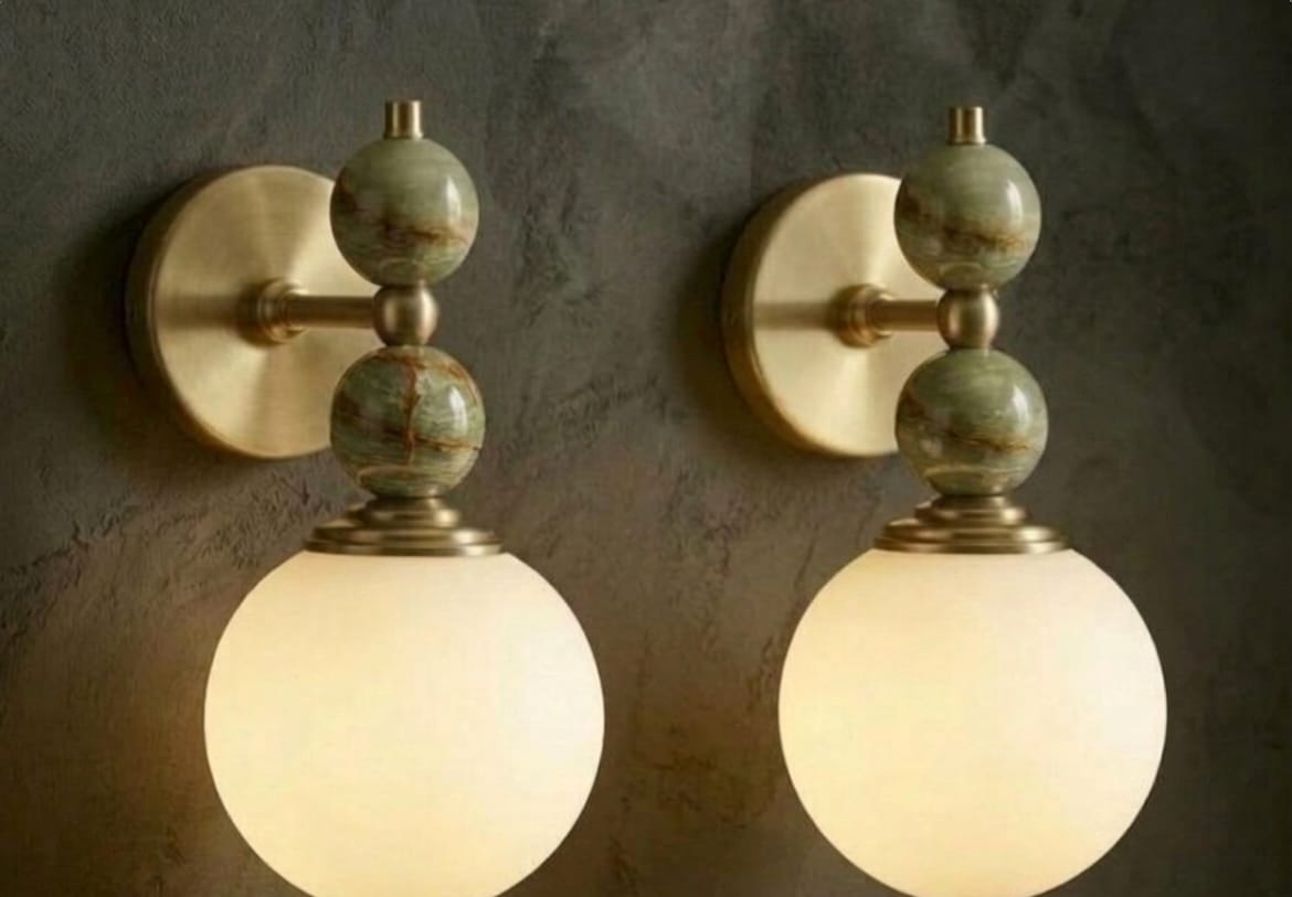 Hand adjusting a wall-mounted light fixture with marble accents on a plain wall.