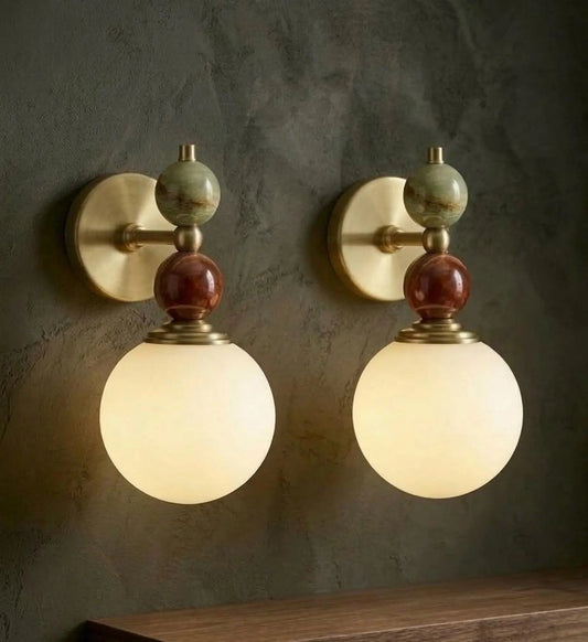 Pair of wall sconces with spherical glass shades on a textured wall.