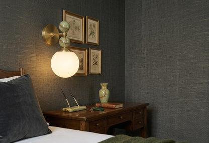 Hand adjusting a wall-mounted light fixture with marble accents on a plain wall.