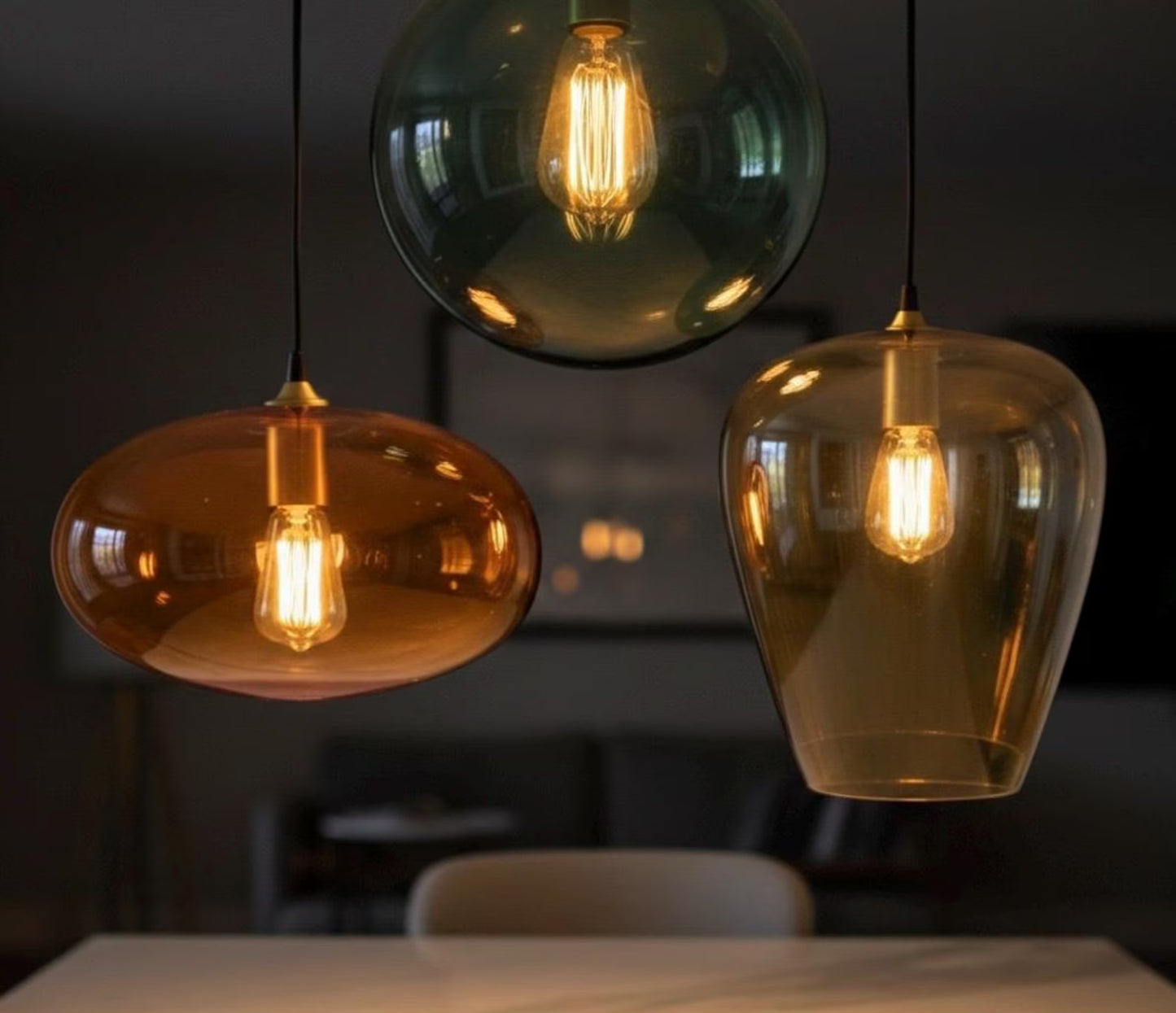 Three pendant lights with glass shades hanging above a table | Les Trois Pyramides.