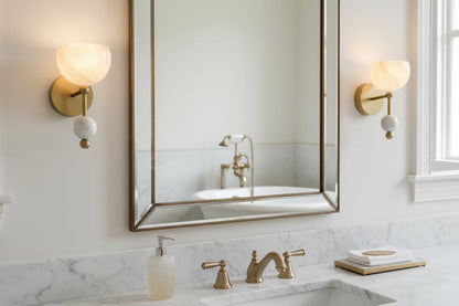 Bathroom with marble countertop, sink, and mirror with gold fixtures.