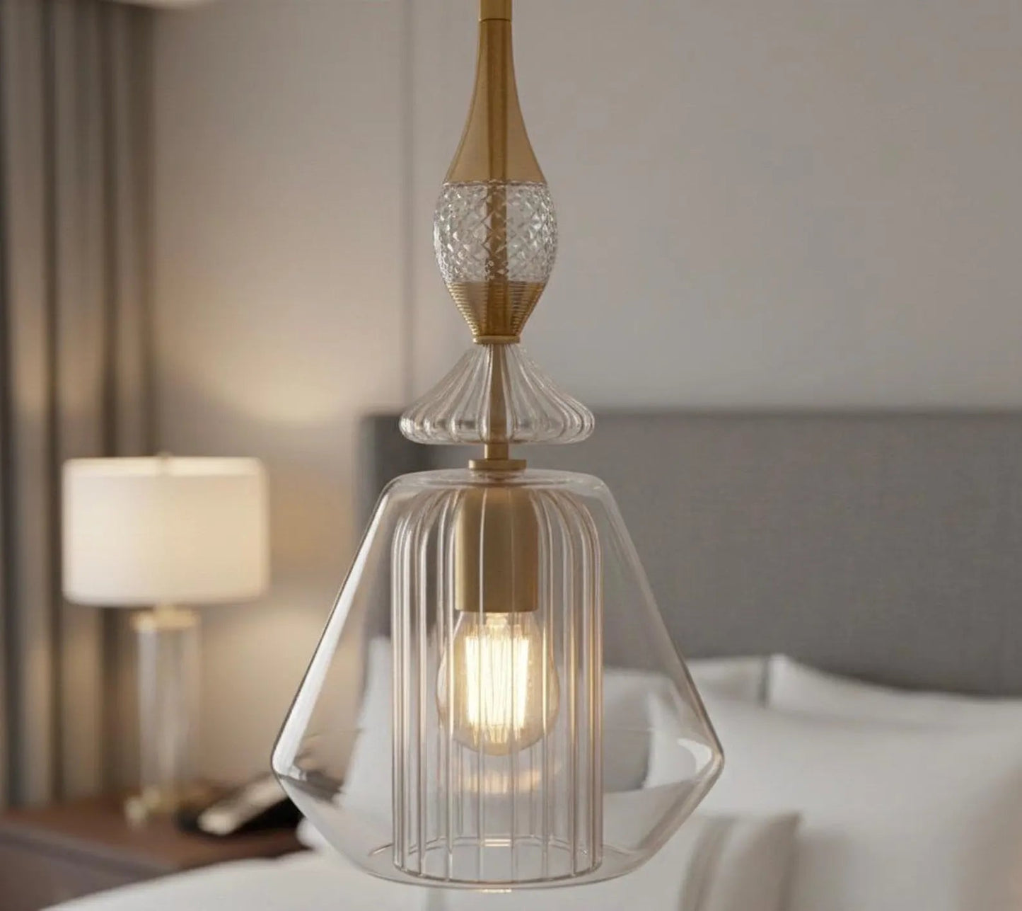Decorative pendant light with clear glass shade and gold accents in a bedroom setting.
