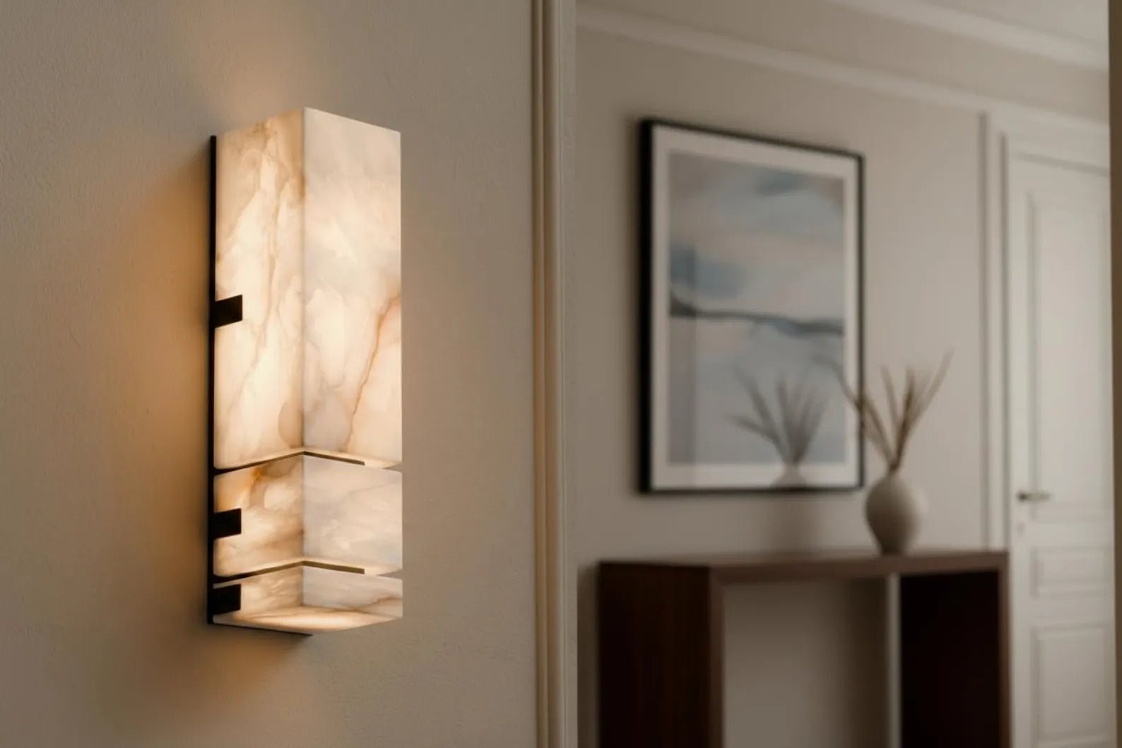 Wall-mounted light fixture in a room with a painting and vase on a shelf.