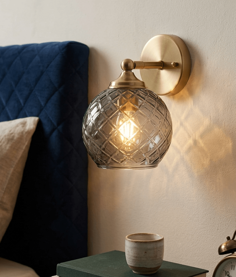 Wall-mounted smokey grey glass lamp with textured glass shade in a cozy room setting - Les Trois Pyramides