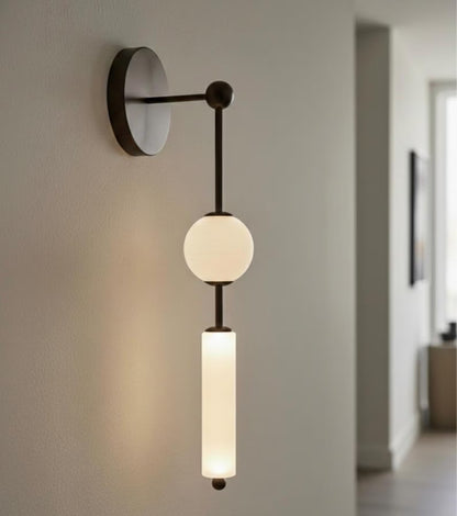 Modern wall-mounted light fixture with two glass shades on a neutral wall.