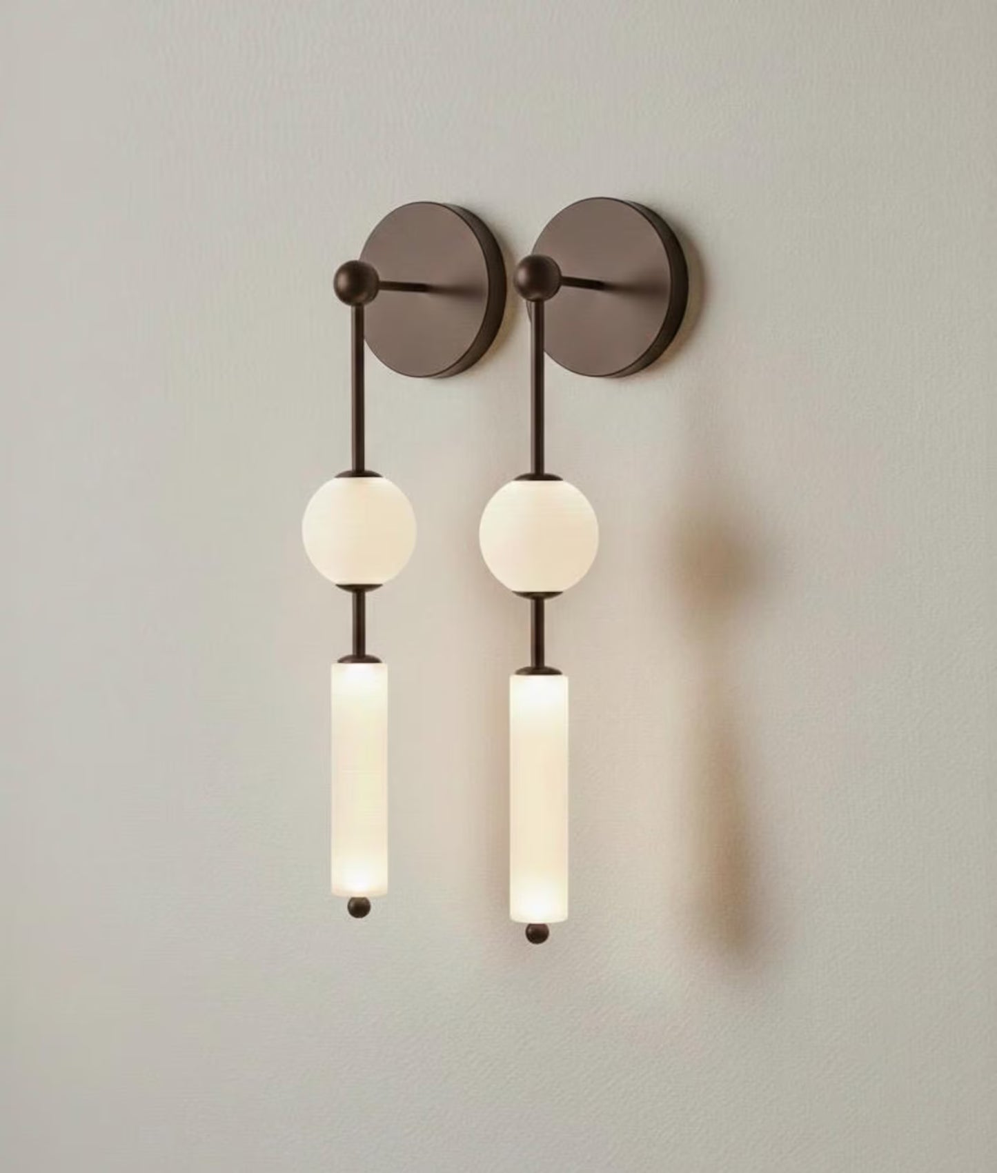Modern wall sconce with three light bulbs on a plain wall.
