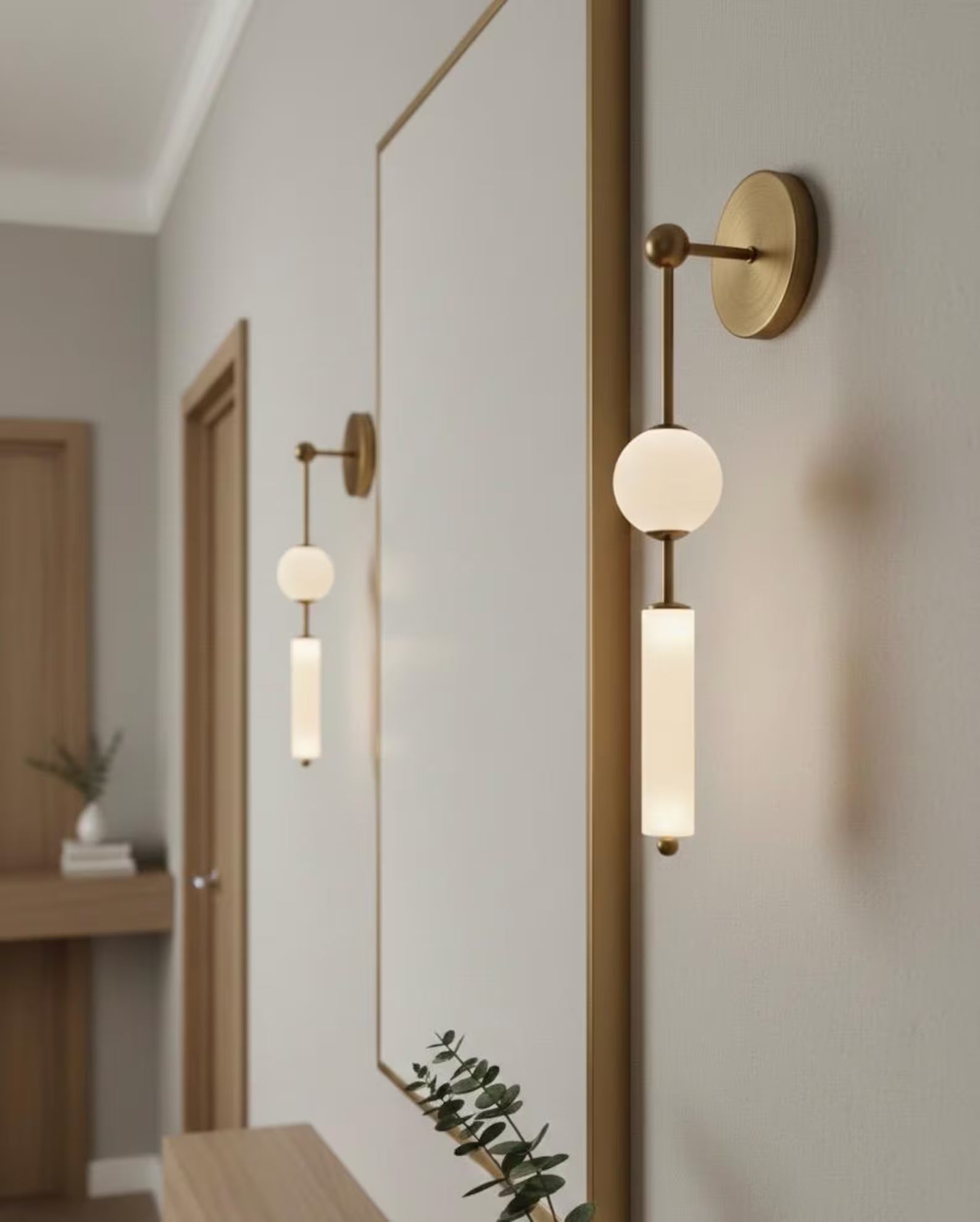 Modern wall sconces with gold frames and white glass shades in a home interior setting.