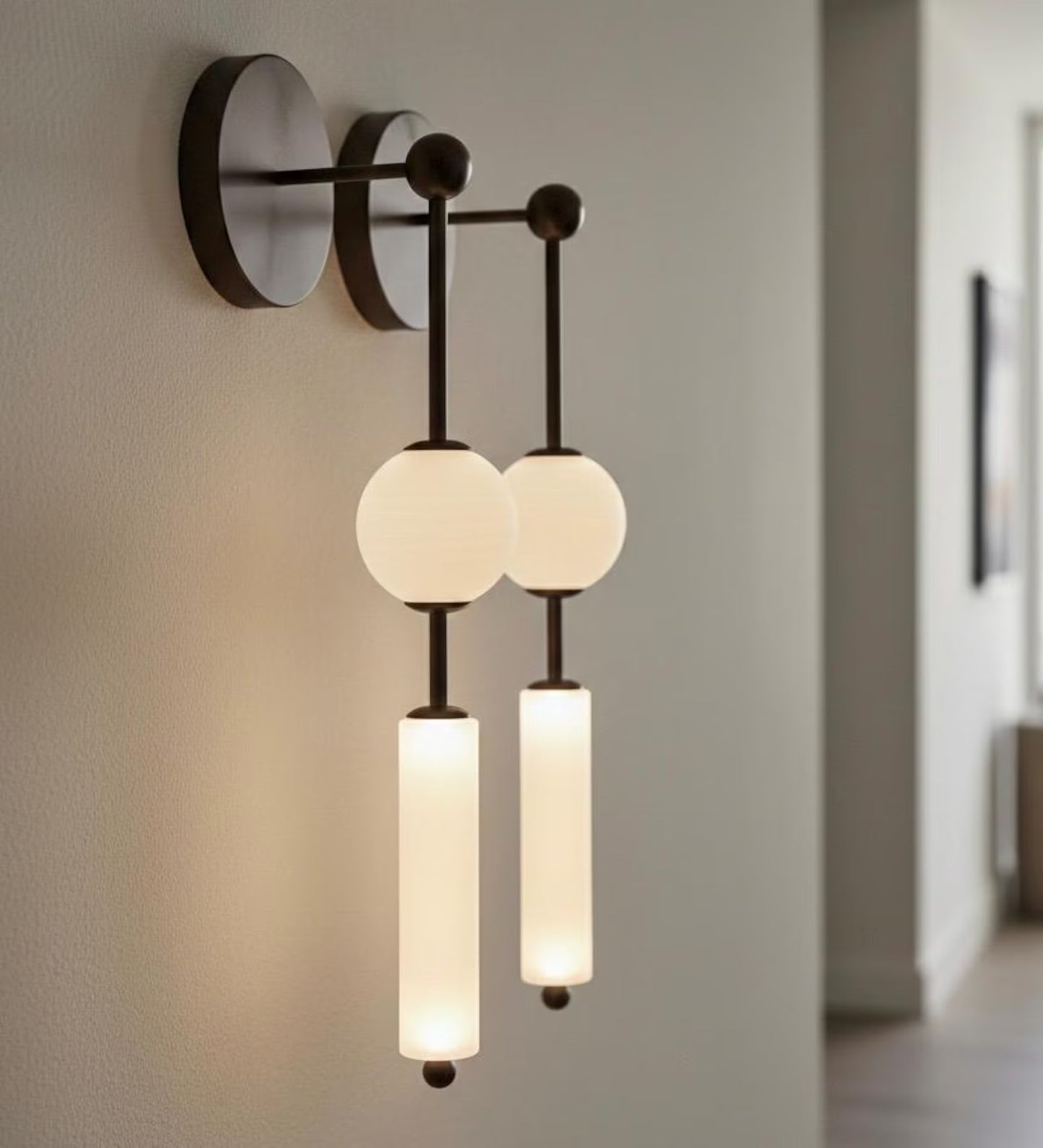 Modern wall-mounted light fixture with three illuminated glass shades on a neutral wall.