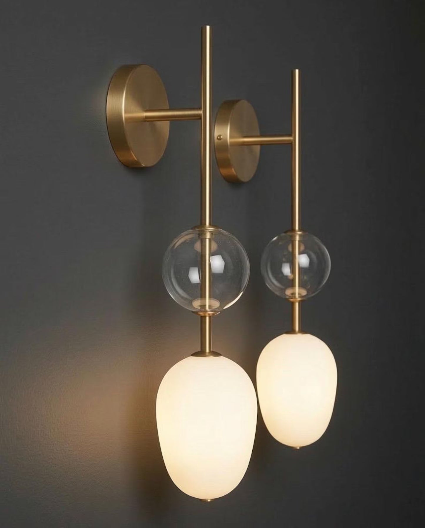 Modern wall-mounted light fixture with glass shades on a dark background