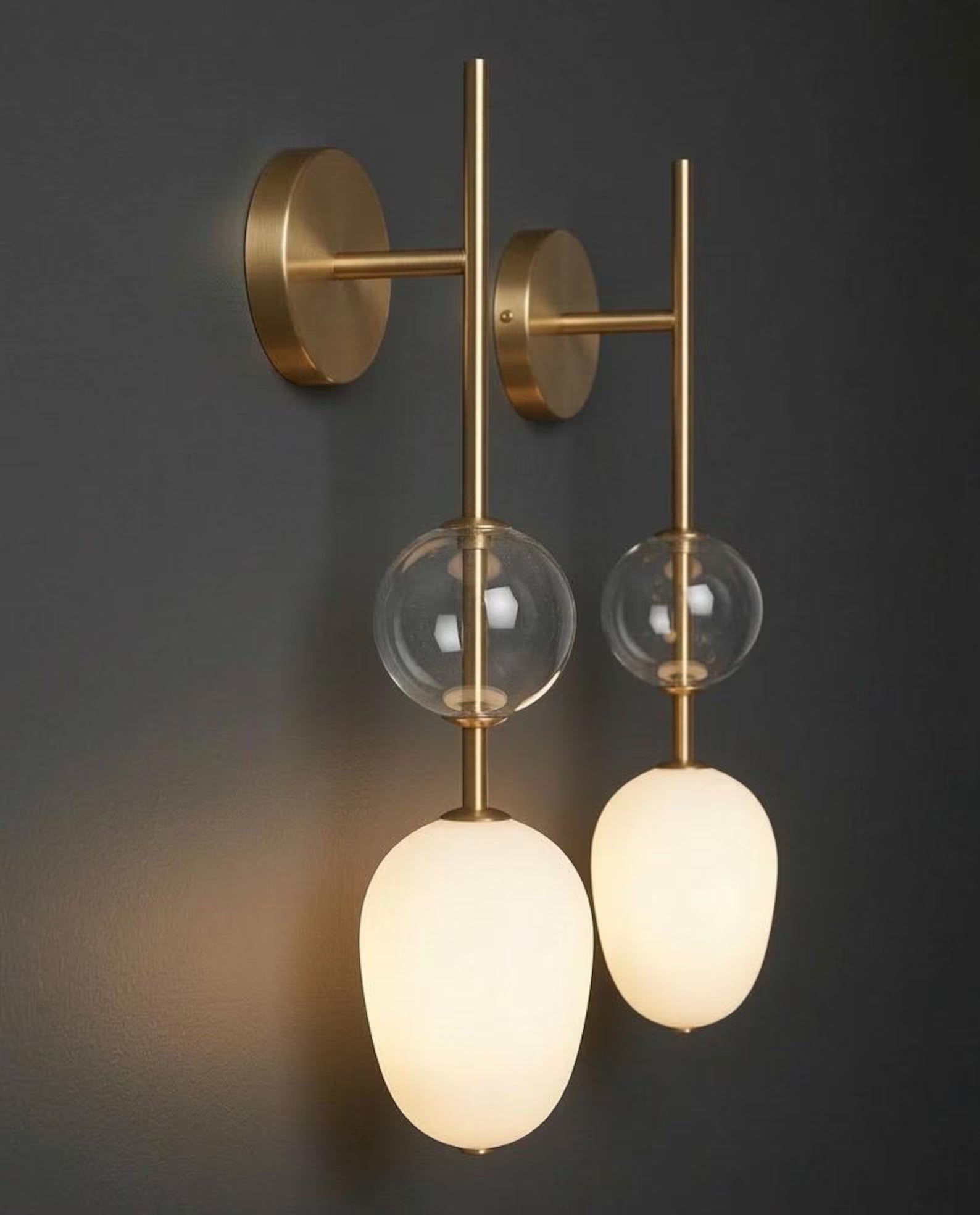 Modern wall-mounted light fixture with glass shades on a dark background